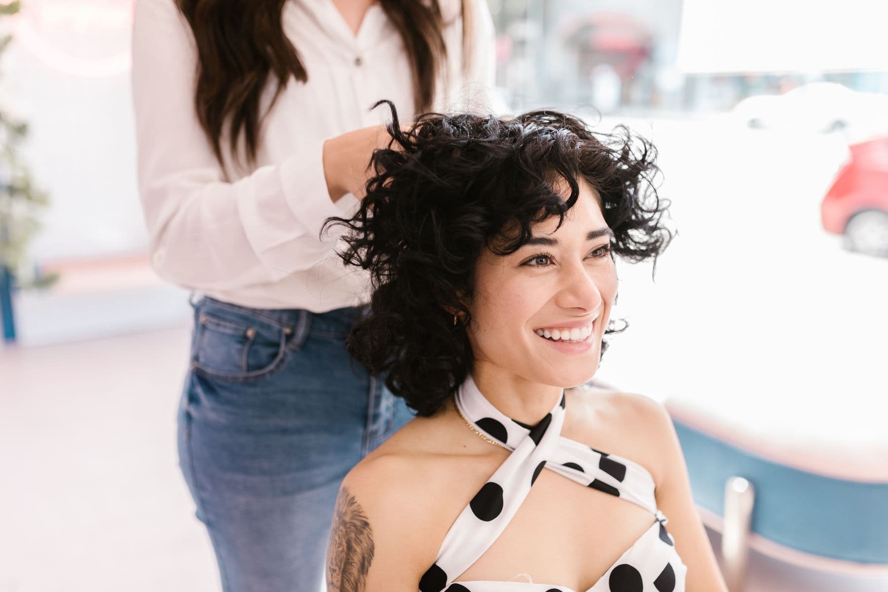 Profissional modelando o cabelo cacheado de uma cliente em um salão