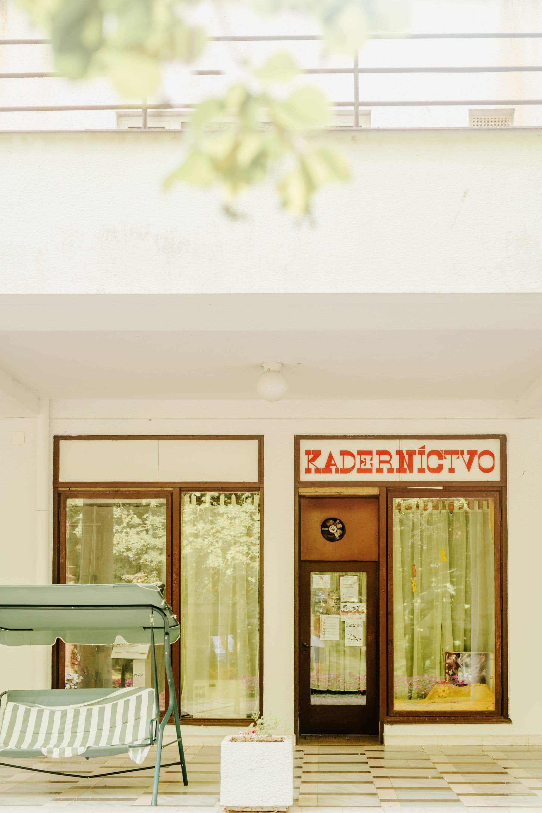 Fachada real de um salão de cabelo em uma rua arborizada